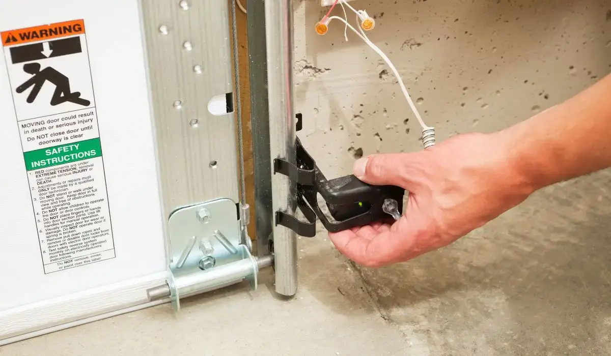 Technician adjusts garage door sensor to restore garage door functionality affected by seasonal moisture in Chicagoland.