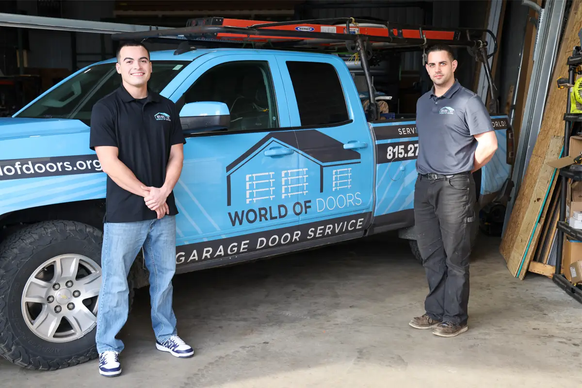 Owners of World of Doors standing beside their branded truck in New Lenox, IL, representing their commercial door repair company and garage door services.