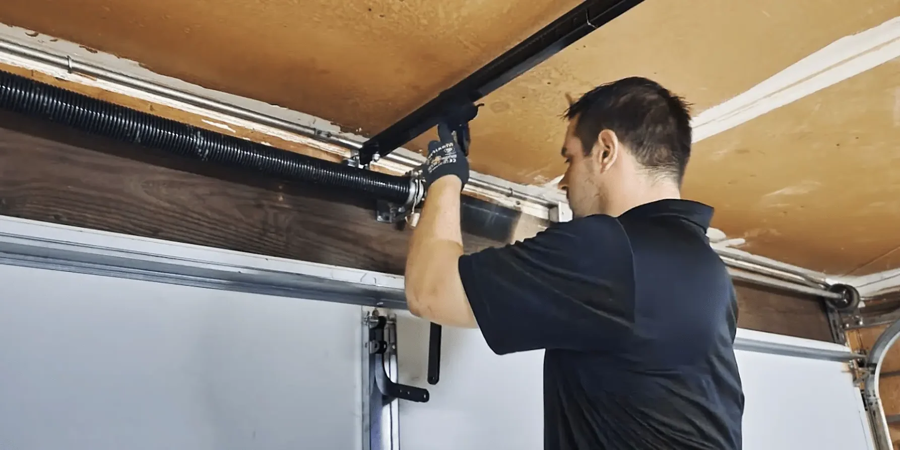 Technician performing garage door tune-ups by adjusting spring tension to ensure smooth, safe, and reliable operation.