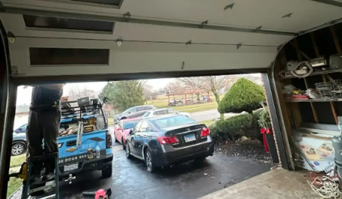 Technician performing repair on residential garage door panels to assess alignment, functionality, and visible surface damage.