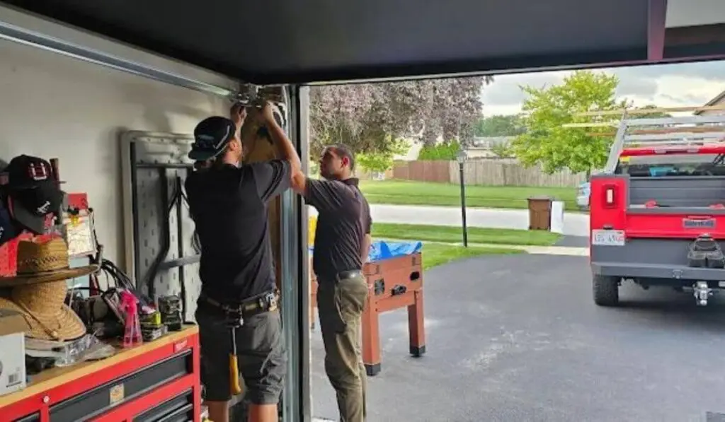 Technicians adjusting the garage door opener during a repair session.